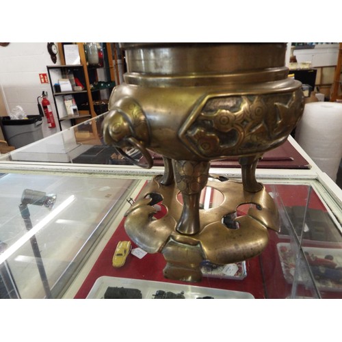 23 - A bronze Oriental tripod censer with a Fu dog mounted on cover and animals and bird decoration in re... 