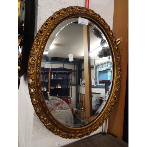 324 - An ornate gilt painted oval mirror