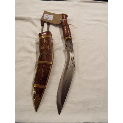 130 - A teak handle ornamental Kukri in wooden and brass inlaid scabbard