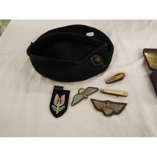 155 - A vintage tobacco tin, three SAS cloth insignia, two penknives and a beret