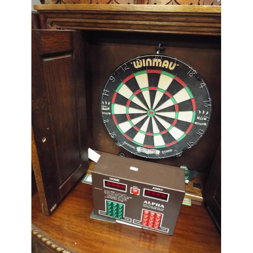 670 - An oak cased dart board cabinet with dart board and darts with electronic scoreboard, no cable for s... 