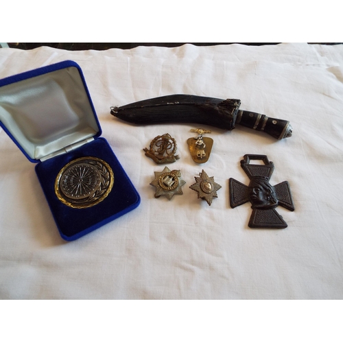 106 - A mixed selection of items to include kukri, military buttons and badges etc