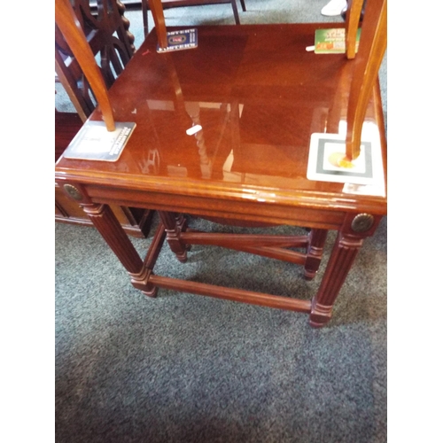 606 - A polished mahogany nest of three tables, two having drop leaves with brass handles and carved carto... 