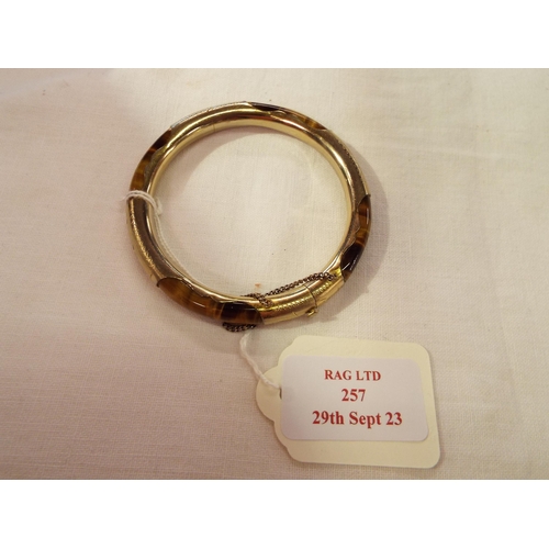 257 - A tiger eye bangle with yellow metal mounts