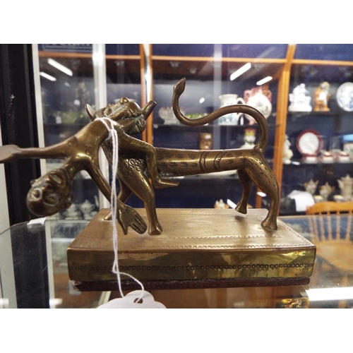 166 - A brass Indian model of a lion holding a man in his mouth mounted on a brass and wooden base