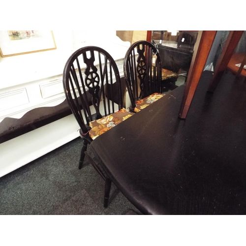 514 - A black stained drop leaf table and four wheel and stick back chairs