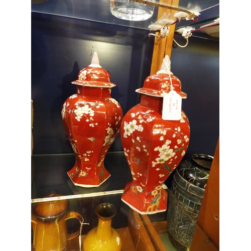 56 - A pair of Oriental vases of a brown/red colour decorated with prunus with lids 12