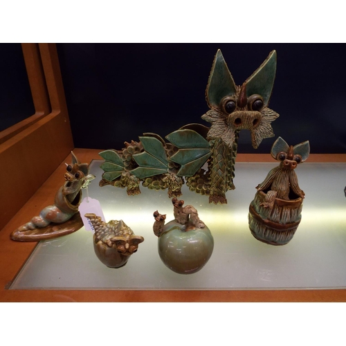 18 - A vintage Yare six legged pottery dragon together with one in climbing out of a barrel, one in a con... 