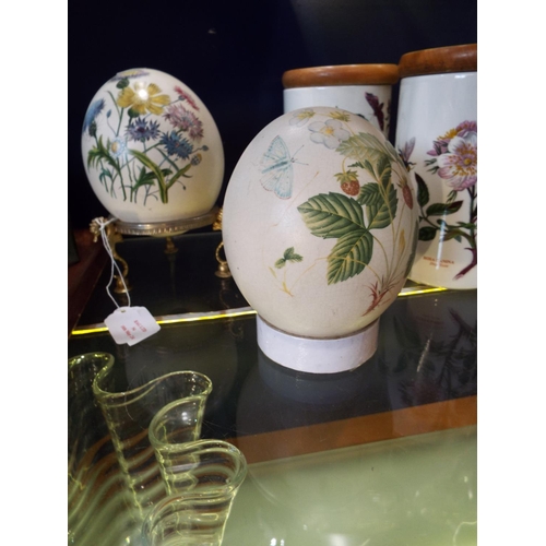 54 - Two Cinque Ports Pottery Ostrich eggs with floral decoration, one resting on a metal stand