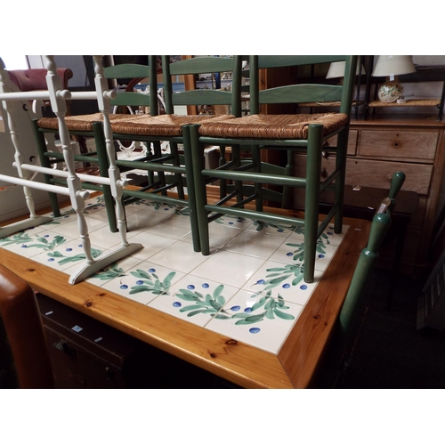 562 - A pine and tiled top kitchen table with berry decoration and a set of six ladder back and rush seat ... 