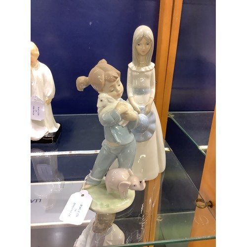 18 - A Valencia figurine of a girl with bonnet and a Nao figurine of a girl with lamb and elephant