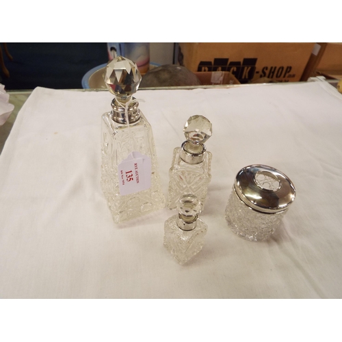 135 - A cut glass hair tidy with a 1912 silver top together with three cut glass scent bottles with silver... 