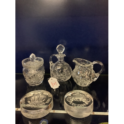 43 - A cut glass oil bottle, cream jug, preserve pot and two commemorative glass paperweights