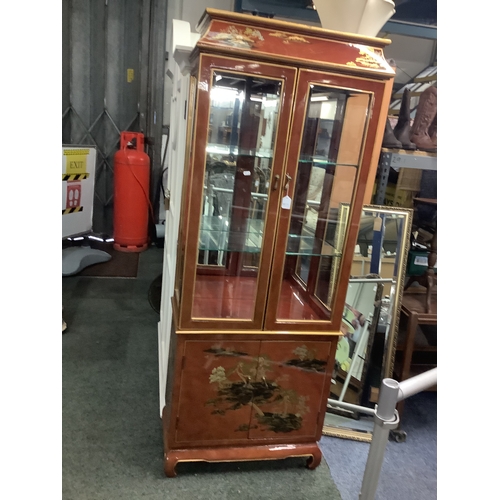 583 - A Chinese red lacquered chinoiserie decorated glass display cabinet the top having glazed doors abov... 