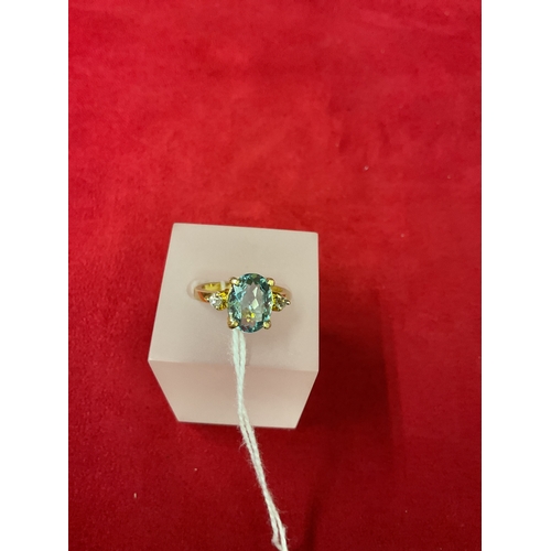 317A - An 18ct gold ring inset with central oval aquamarine flanked by diamonds, size M