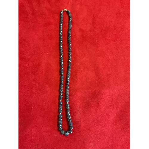 309 - A natural faceted sapphire beaded necklace with red toning and 9ct gold clasp