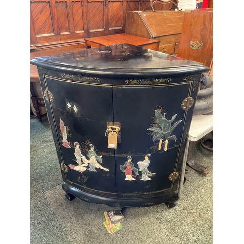 608 - An Oriental black lacquered corner bow-front cabinet with chinoiserie decoration of semi-precious st... 