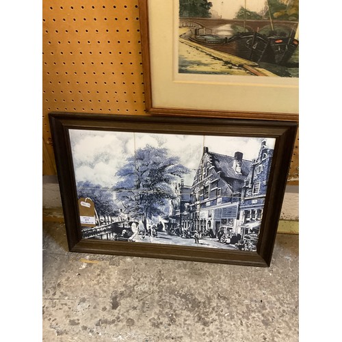477 - A wooden framed Delft wall plaque depicting a Dutch street and river scene