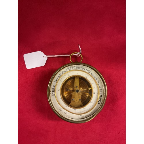 A vintage round cased brass aneroid barometer