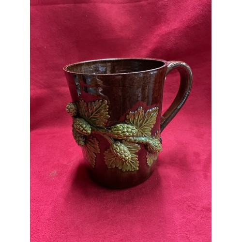 55 - A Sussex art ware Rye Pottery tankard with applied hop and vine decoration (repair to handle)