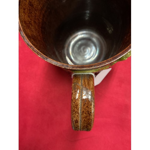 55 - A Sussex art ware Rye Pottery tankard with applied hop and vine decoration (repair to handle)