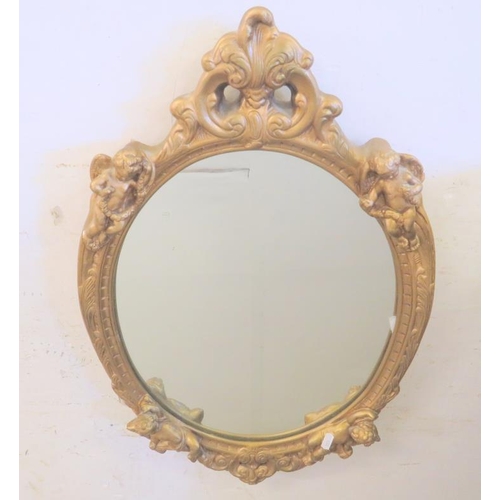 15 - Plaster Framed Gilt Oval Wall Mirror decorated with cherubs approx. 68cm x 44cm (FRONT WALL)