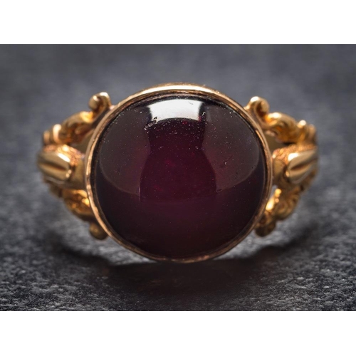 1119 - A cabochon garnet single-stone ring: in closed-back setting and between splayed shoulders, ring size... 