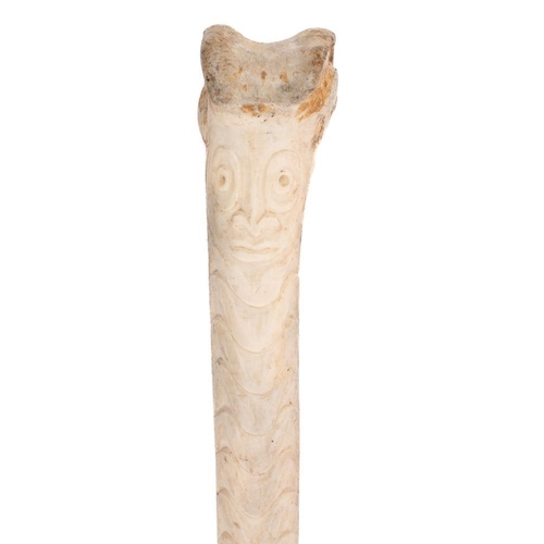 150 - A carved bone fid, possibly African in origin:  carved from a femur with mask decoration beneath pat... 