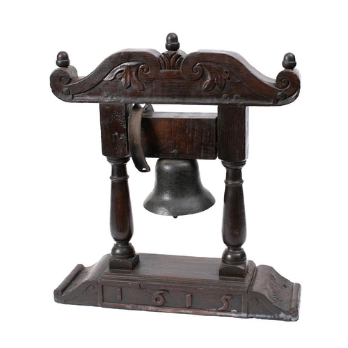 314 - A Continental bell: on an oak portico stand, the shaped top with foliate carving and acorn finials o... 