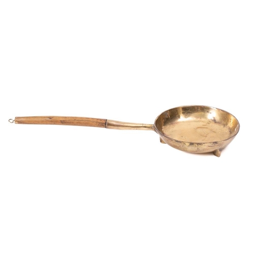 116 - A Bell metal circular frying pan: with turned wood handle, on tripod feet, 23cm diameter.