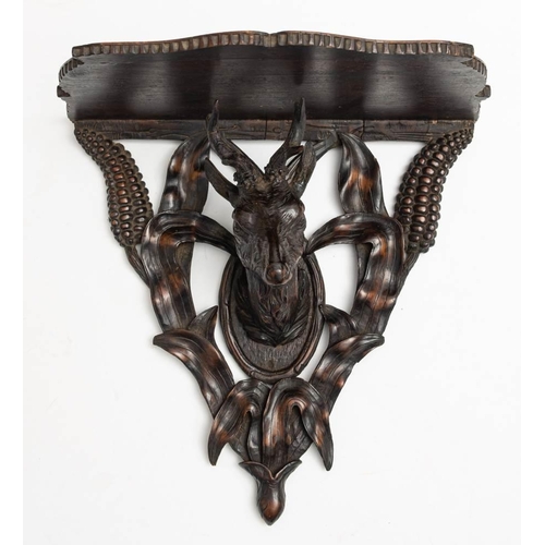 121 - A late 19th/early 20th century Black forest carved wood wall bracket: the shaped open shelf on a car... 