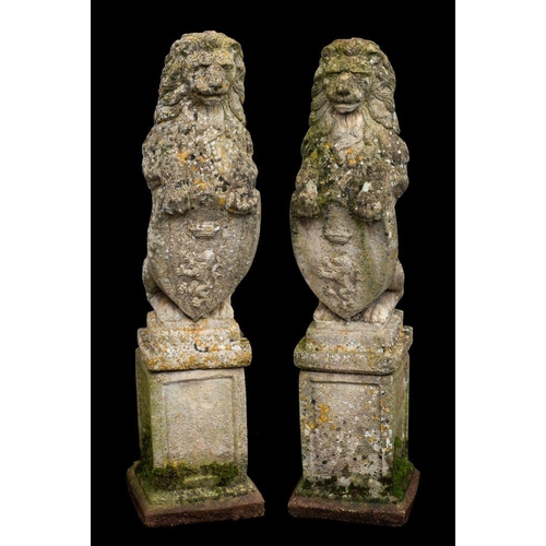 1448 - A pair of stone composition garden models of heraldic lions, 20th century; each portrayed as sejant ... 