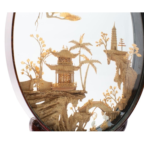 432 - A Chinese carved diorama of oval outline depicting a pagoda landscape with bridge and cranes, on a s... 