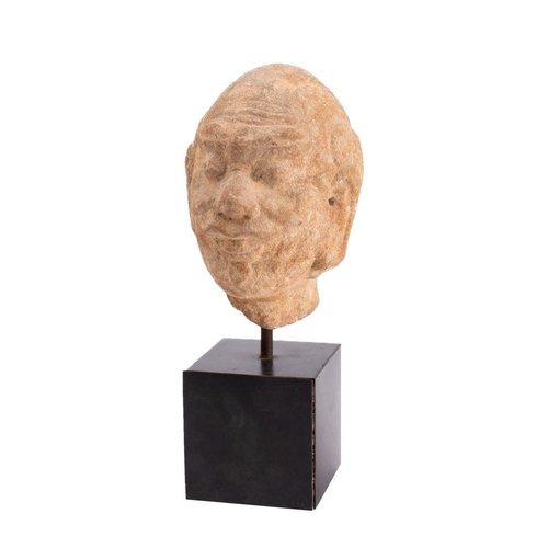 561 - An Indian carved sandstone head of a moustachioed man with shaved head, furrowed forehead, bushy eye... 