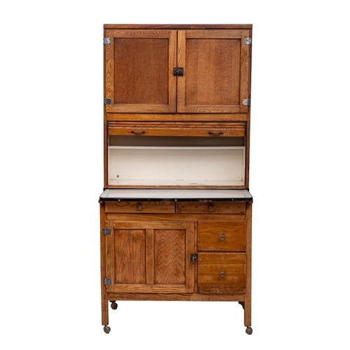 110 - An oak kitchen dresser, circa 1925; the upper section with twin panel doors above a tambour drop fro... 