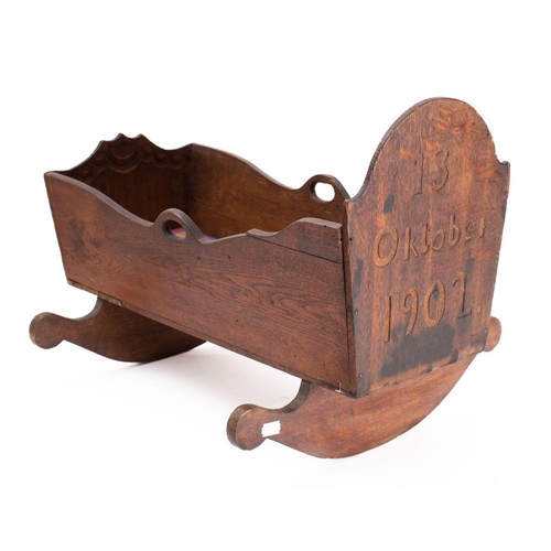 843 - An early 20th century Danish oak crib, carved and dated '13 Oktober 1902', raised on sleigh rockers,... 