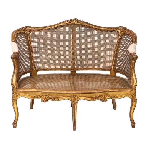 1049 - A giltwood and canework settee in Louis XV style, late 19th /early 20th century; the channeled topra... 