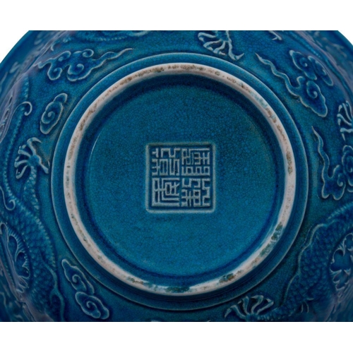 116 - A Chinese blue ground 'Dragon' bowl: the exterior decorated in relief with three scally dragons amon... 