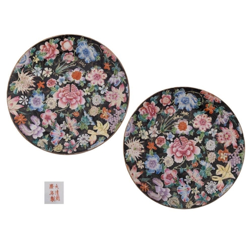 118 - A pair of Chinese famille noire millefleurs plates painted with brightly coloured blooms on a black ... 