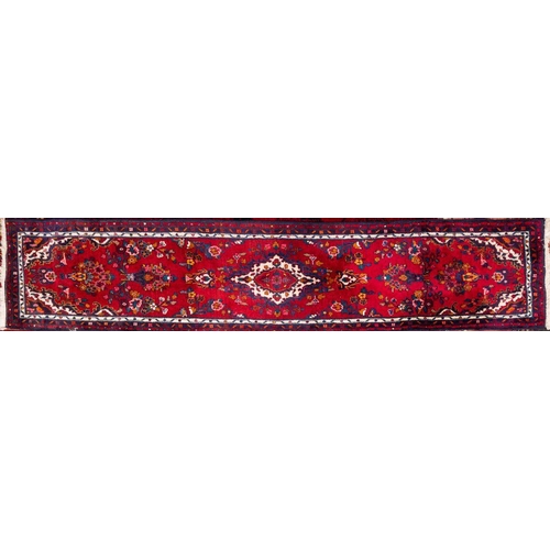 1369 - An Iranian Runner, the red field with a central ivory shaped lozenge pole medallion all over floral ... 