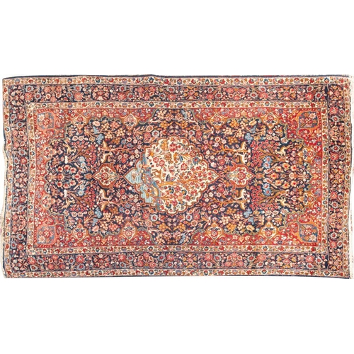 1376 - A Kirman Carpet,  the indigo cartouche field with a central cartouche pole medallion with a design o... 