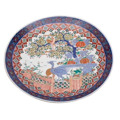 143 - A large Japanese Arita charger decorated in under glaze blue, red, green and yellow enamel with a pa... 