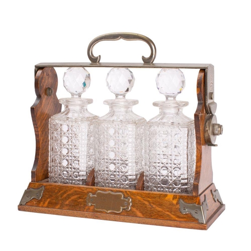 A Victorian oak and silvered metal mounted three-decanter tantalus ...