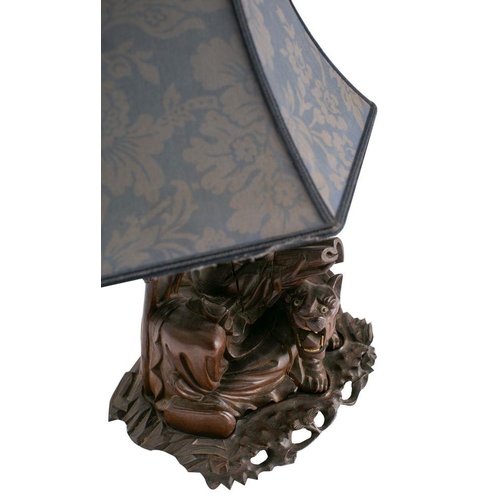 584 - A Chinese carved hardwood table lamp depicting an Immortal seated with a tiger and reading a book, o... 