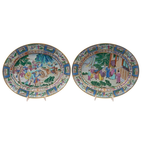 77 - A fine pair of Canton oval serving dishes decorated in bright enamels, one with a Court pavilion pre... 