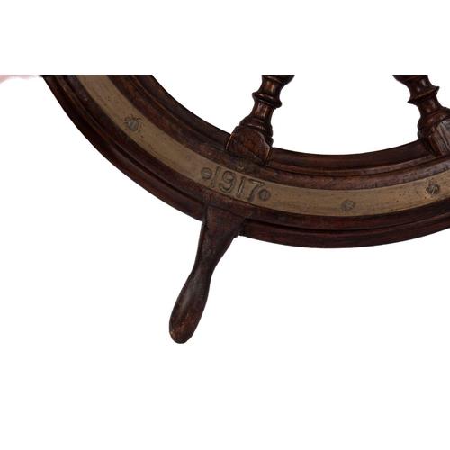 199 - A WWI period teak and brass ship's helm: with block and turned spars, the brass rim inscribed and da... 