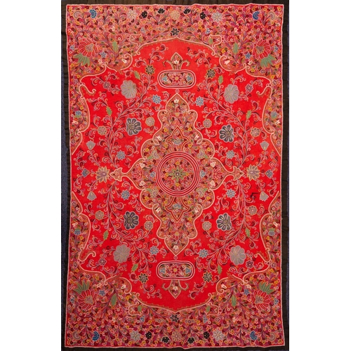 1200 - A Persian silk embroidered table cover worked with an arabesque design of stylised flowers and scrol... 