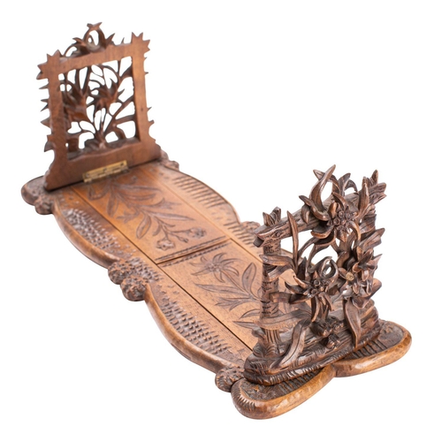 294 - A 'Black Forest' carved limewood book slide, probably Swiss, circa 1900; the hinged openwork ends mo... 