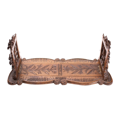 294 - A 'Black Forest' carved limewood book slide, probably Swiss, circa 1900; the hinged openwork ends mo... 