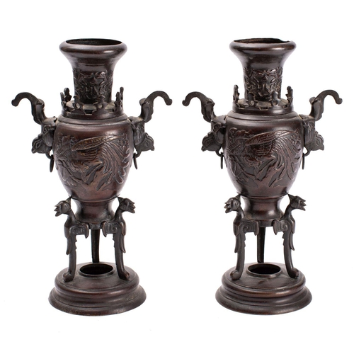 387 - A pair of Japanese bronze two-handled vases cast in relief with ho-o birds and on tripod supports an... 